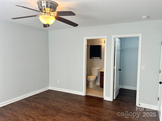 unfurnished bedroom with ensuite bathroom, ceiling fan, dark wood-type flooring, a closet, and a walk in closet