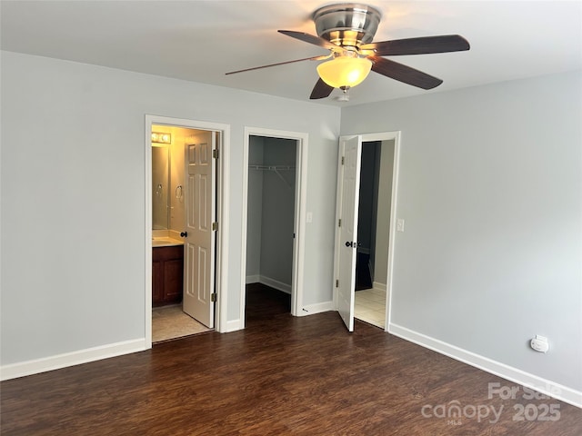 unfurnished bedroom featuring a spacious closet, ensuite bathroom, ceiling fan, a closet, and dark hardwood / wood-style flooring