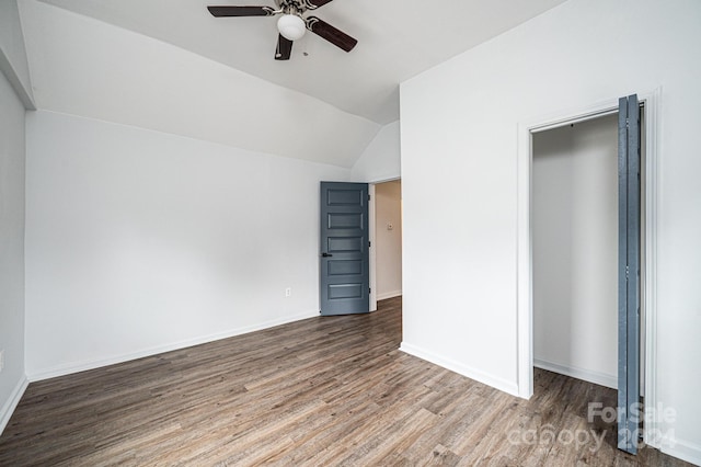 unfurnished bedroom with lofted ceiling, a closet, wood-type flooring, and ceiling fan