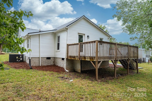 rear view of property with a wooden deck and a lawn