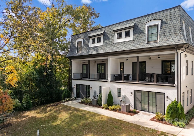 view of front facade featuring a balcony, a front yard, central AC unit, and ceiling fan