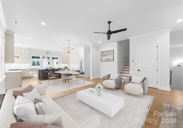 living room with ornamental molding, ceiling fan with notable chandelier, and light hardwood / wood-style floors