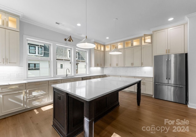 kitchen featuring light stone countertops, sink, backsplash, a center island, and stainless steel fridge