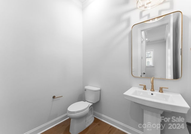 bathroom featuring ornamental molding, sink, wood-type flooring, and toilet