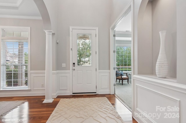 entryway with dark wood-type flooring, ornate columns, and ornamental molding