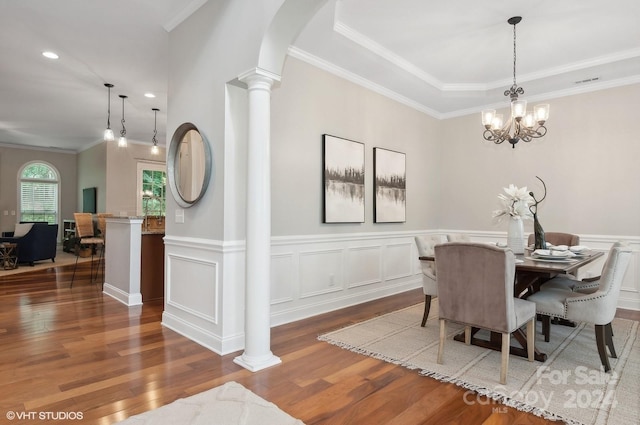 dining room with crown molding, hardwood / wood-style flooring, a chandelier, and ornate columns