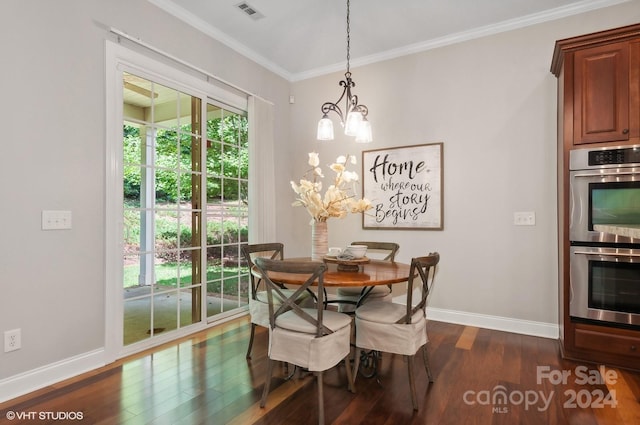 dining area with dark wood-type flooring, crown molding, and a notable chandelier