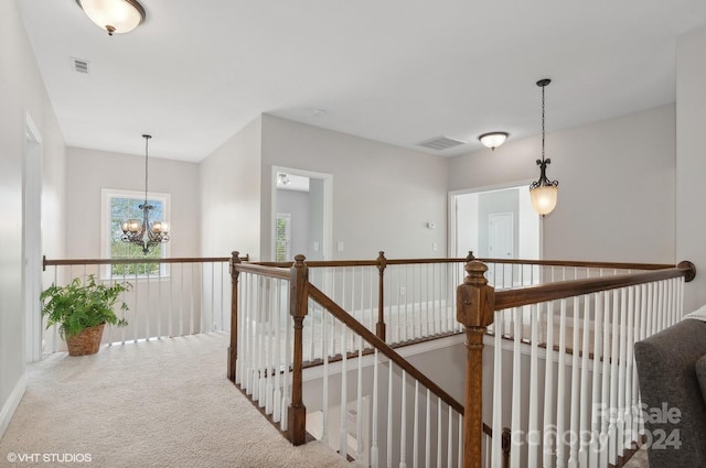 hall with a notable chandelier and carpet floors