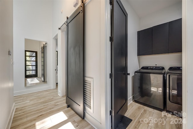 interior space featuring light wood-type flooring, cabinets, separate washer and dryer, and a barn door