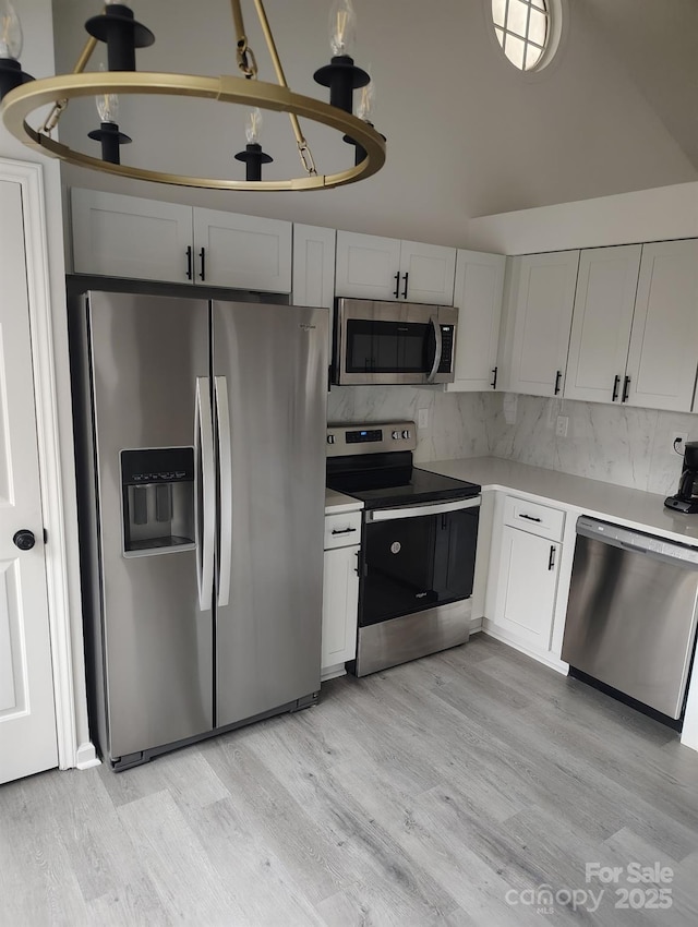 kitchen featuring white cabinets, tasteful backsplash, stainless steel appliances, and light hardwood / wood-style flooring