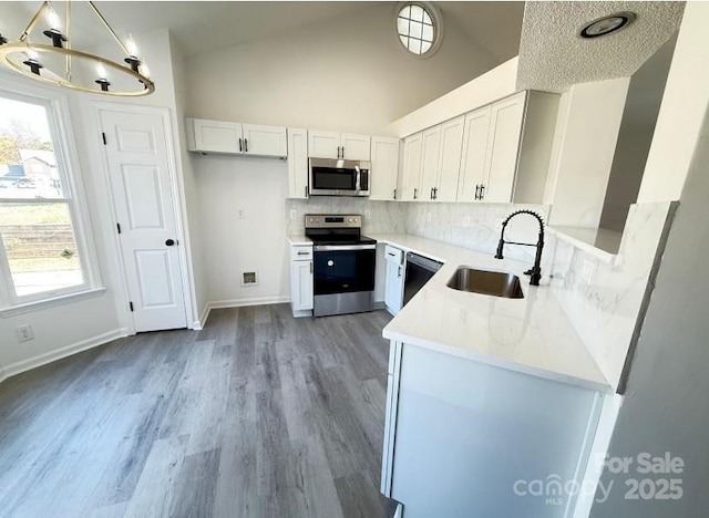 kitchen featuring sink, stainless steel appliances, hanging light fixtures, and white cabinets