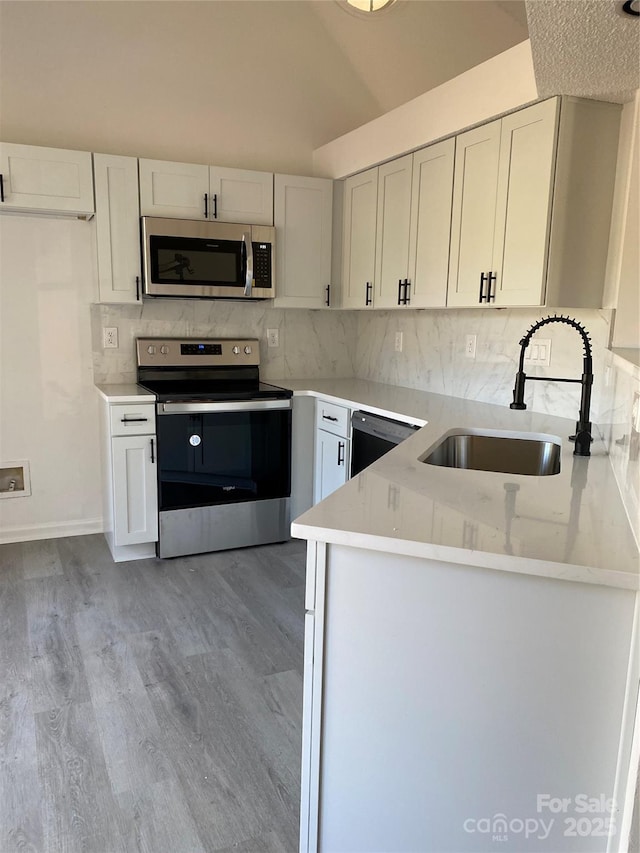 kitchen featuring sink, white cabinetry, stainless steel appliances, kitchen peninsula, and decorative backsplash