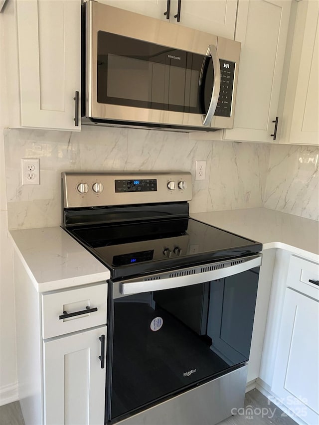 kitchen featuring backsplash, appliances with stainless steel finishes, white cabinets, and light stone counters