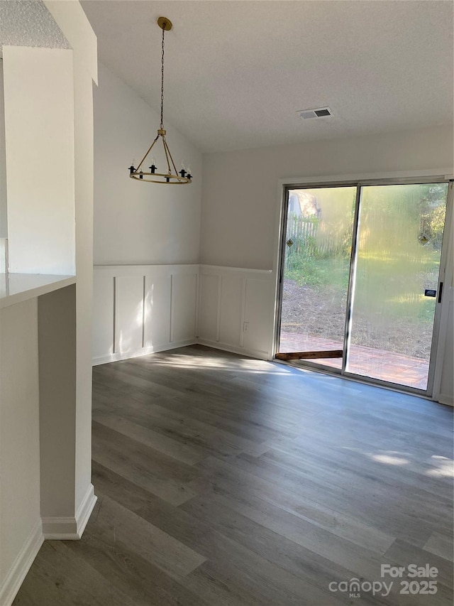 unfurnished dining area with vaulted ceiling, a chandelier, and dark hardwood / wood-style floors