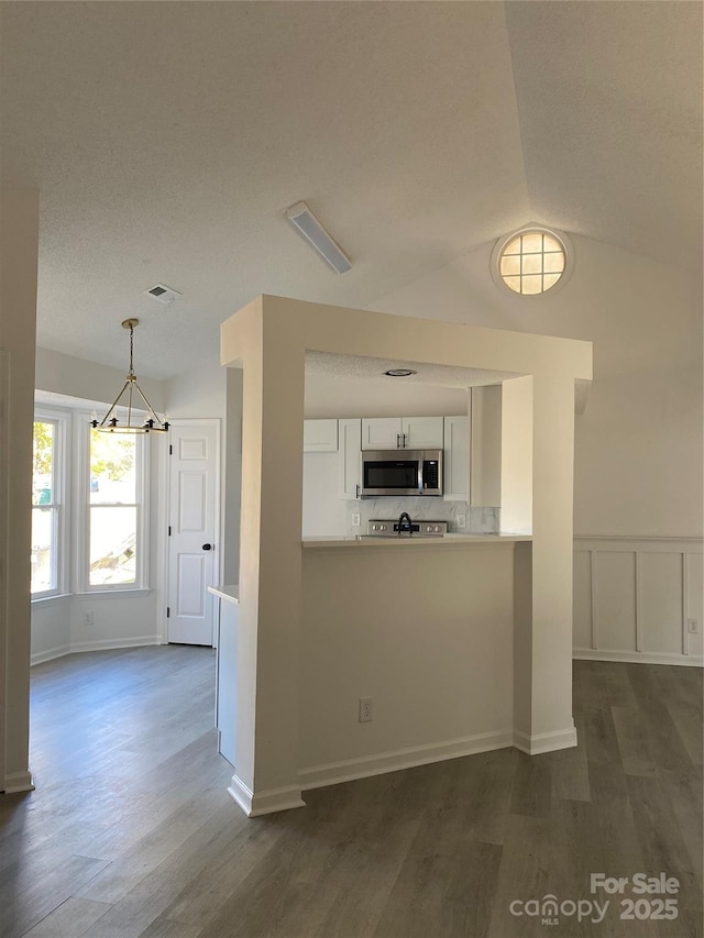 kitchen featuring white cabinets, pendant lighting, dark wood-type flooring, and vaulted ceiling