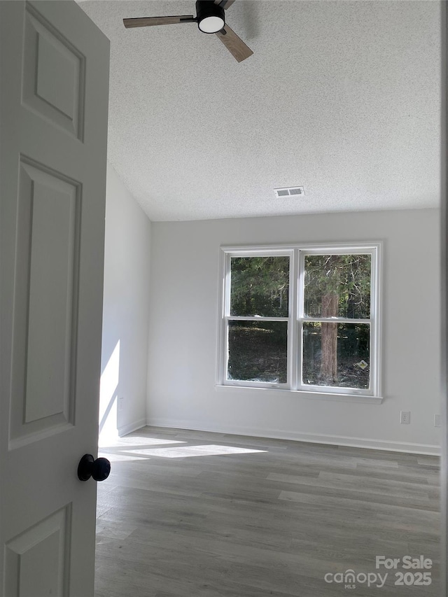 empty room with a textured ceiling, hardwood / wood-style floors, and ceiling fan