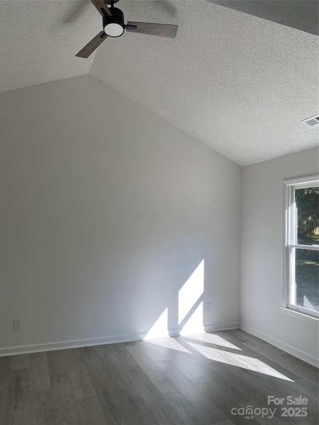 empty room with ceiling fan, dark wood-type flooring, a textured ceiling, and lofted ceiling