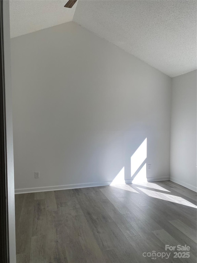 unfurnished room featuring vaulted ceiling, dark hardwood / wood-style floors, and a textured ceiling