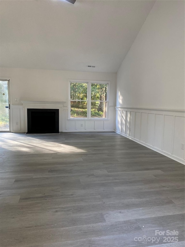 unfurnished living room featuring plenty of natural light, dark wood-type flooring, and vaulted ceiling