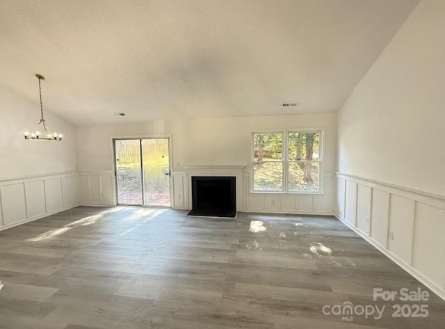 unfurnished living room featuring a notable chandelier, wood-type flooring, and a textured ceiling