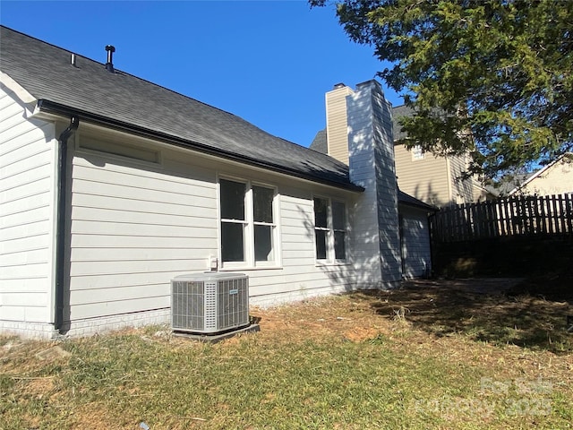 rear view of house with a yard, cooling unit, and a garage