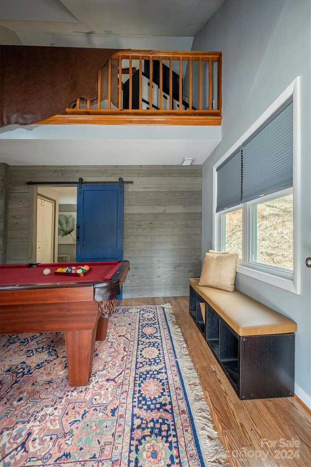 recreation room featuring a barn door, wood-type flooring, billiards, and wood walls