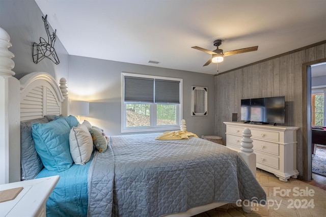 bedroom featuring crown molding, wood walls, light wood-type flooring, and ceiling fan