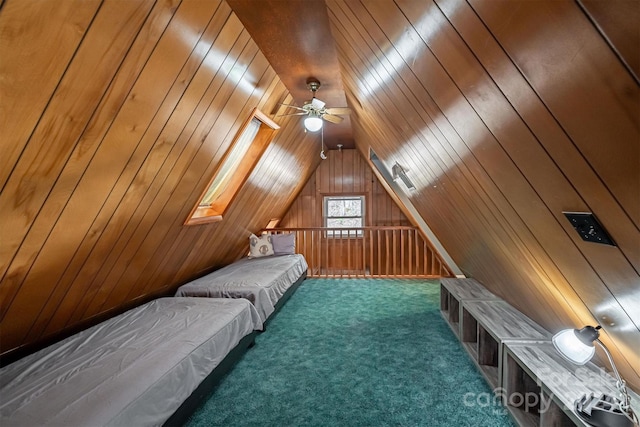 unfurnished bedroom featuring wooden walls, vaulted ceiling with skylight, dark colored carpet, and ceiling fan