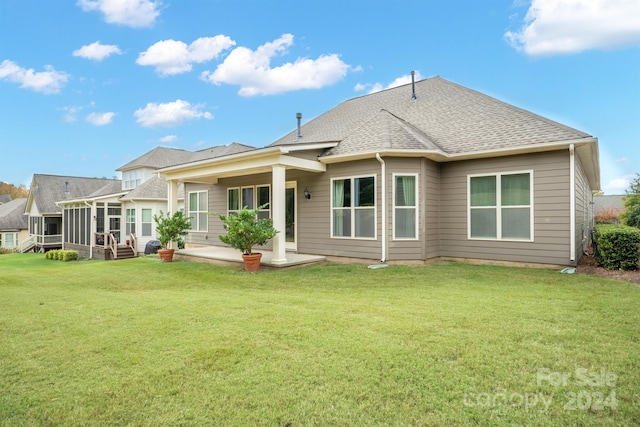 rear view of property with a yard, a patio area, and a sunroom