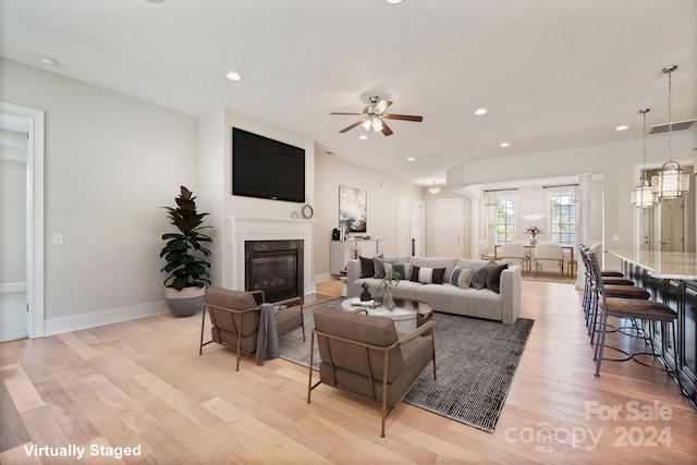 living room with ceiling fan, light hardwood / wood-style flooring, and a fireplace