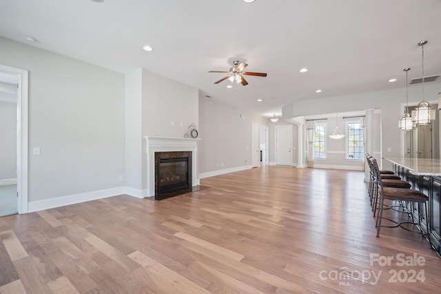 unfurnished living room featuring a high end fireplace, light wood-type flooring, and ceiling fan