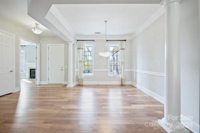 unfurnished dining area featuring ornate columns, light hardwood / wood-style floors, ornamental molding, and a chandelier