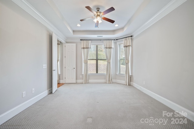 carpeted empty room with crown molding, ceiling fan, and a raised ceiling