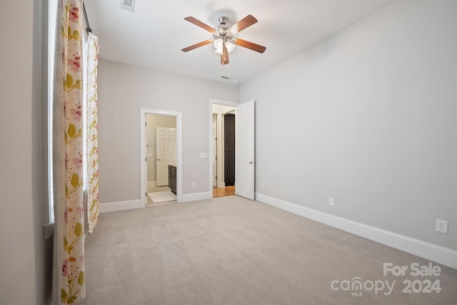 unfurnished bedroom with ensuite bathroom, light colored carpet, and ceiling fan