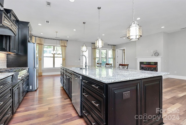 kitchen featuring a large island, hanging light fixtures, backsplash, stainless steel appliances, and sink