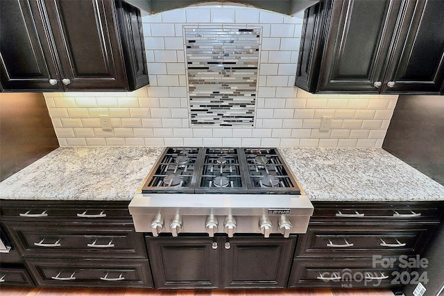 kitchen featuring decorative backsplash, light stone counters, and dark brown cabinets