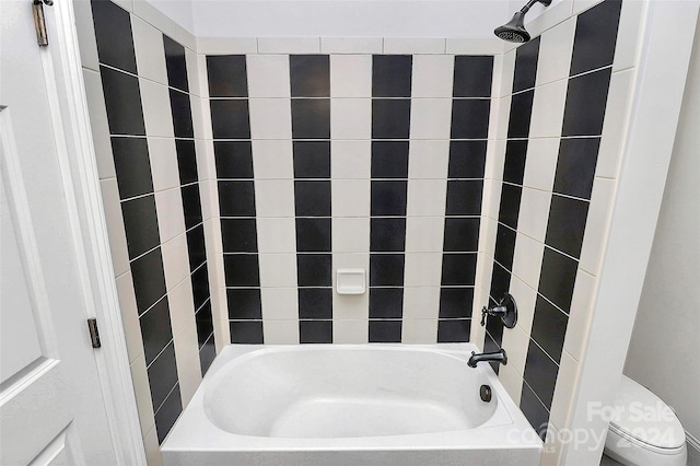 bathroom with toilet and tiled shower / bath