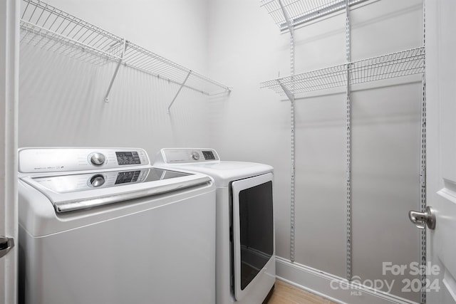 laundry area featuring independent washer and dryer and light hardwood / wood-style floors