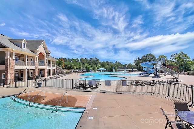 view of swimming pool with a water slide and a patio area