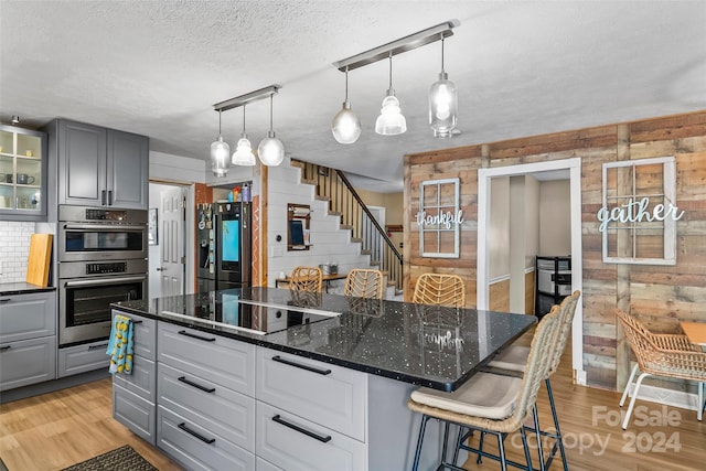 kitchen featuring a breakfast bar area, light hardwood / wood-style flooring, wooden walls, and stainless steel appliances