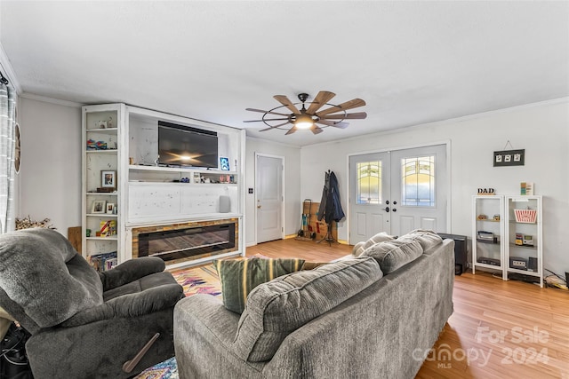 living room featuring light hardwood / wood-style floors, ornamental molding, a fireplace, and ceiling fan