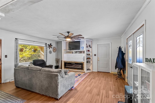 living room featuring crown molding, a textured ceiling, wood-type flooring, and ceiling fan