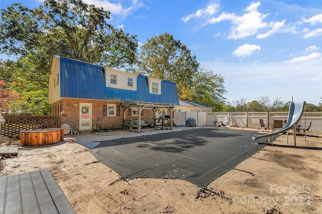 rear view of property with a patio and a pool with hot tub