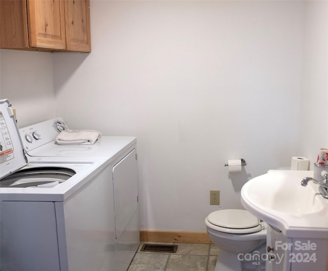 clothes washing area featuring sink, washer and clothes dryer, and light tile patterned floors