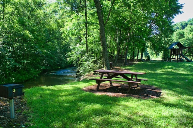 view of property's community with a yard, a water view, and a playground