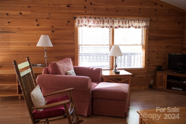 sitting room with light hardwood / wood-style floors, wood walls, and lofted ceiling