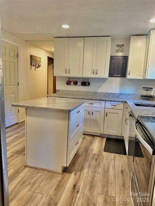 kitchen featuring white cabinetry, light stone countertops, light hardwood / wood-style floors, and electric stove