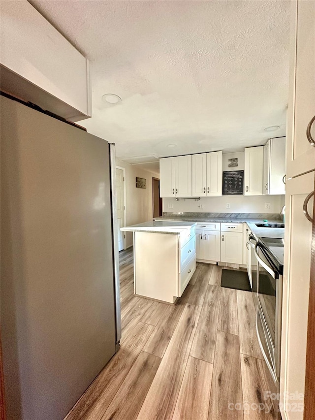 kitchen with sink, white cabinetry, a textured ceiling, stainless steel electric stove, and light wood-type flooring