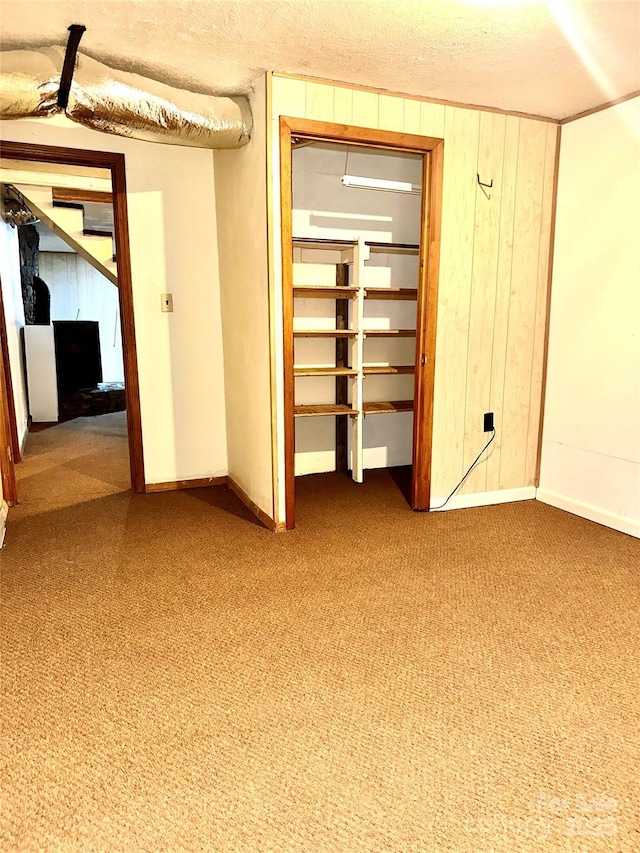 interior space with carpet, a textured ceiling, and wood walls