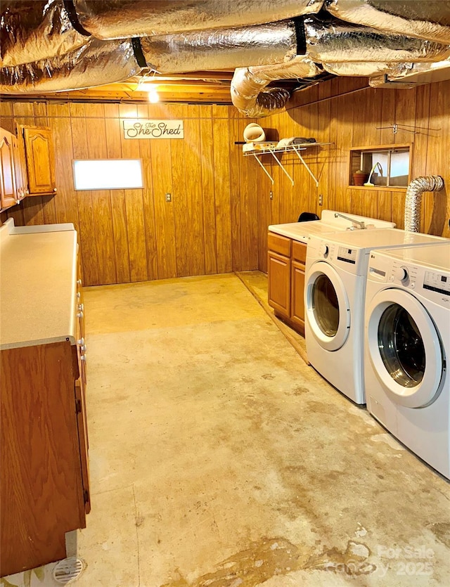 washroom with washer and clothes dryer, cabinets, and wooden walls